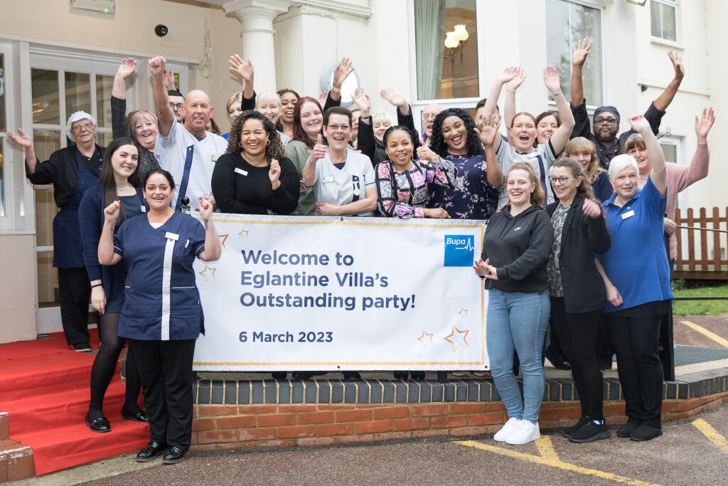 Care home staff hold sign celebrating their Outstanding rating