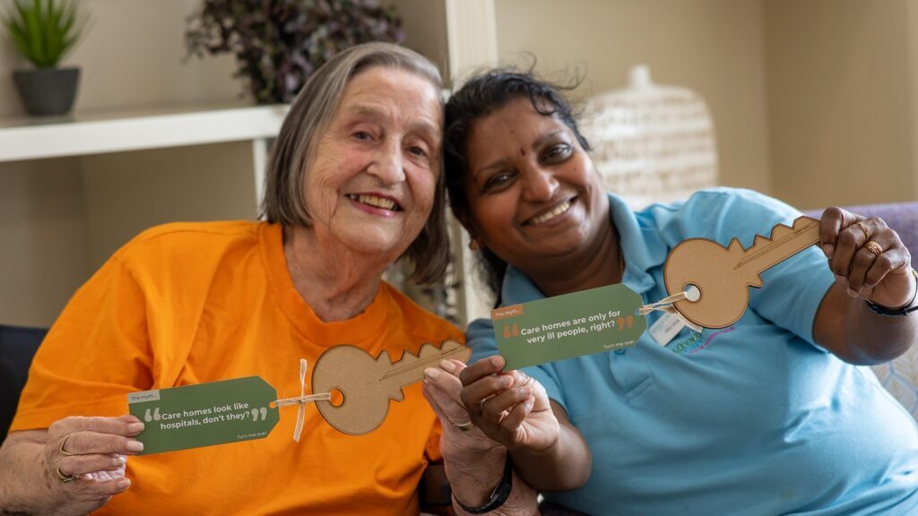 Care home resident Iris and carer Nirmala hold up ‘myth-busting keys’, part of a new campaign to change public perceptions around care homes