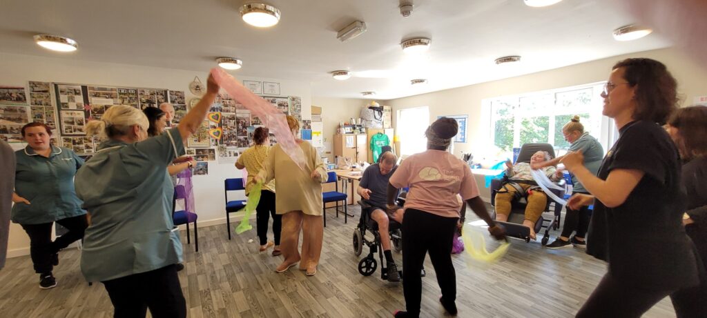 Residents and staff strut their staff during a dance therapy session