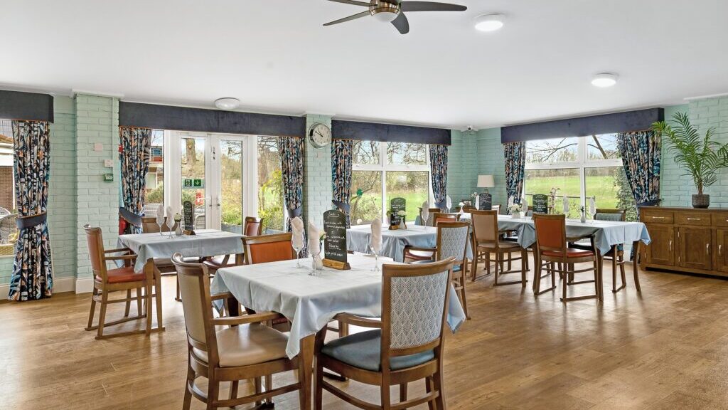 A spacious dining area with views across the garden at Hartford Care's Ashley Grange in Downton