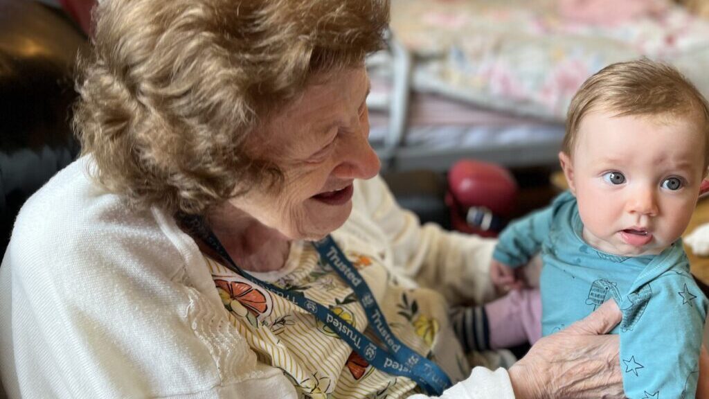 Resident Jean Mountford at RMBI's Prince George Duke of Kent Court in Chislehurst is delighted to meet and hold baby Polly